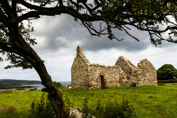 Beautiful old welsh chapel or church, ruin, sky as copyspace top, framed by tree - 654997928