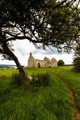 Beautiful old welsh chapel or church, ruin, sky as copyspace top, framed by tree - 654998170