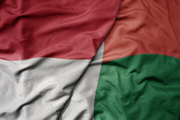 big waving realistic national colorful flag of indonesia and national flag of madagascar .