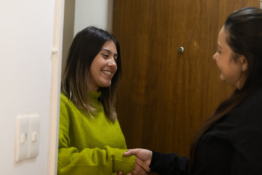 Latin female doctor greeting patient at office door.