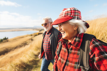 senior couple with white hair wearing plaid shirts smiling walking in the field