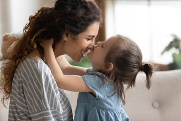 Cute little preschooler daughter hug cuddle with smiling young mother kiss show love and affection, small girl child embrace happy millennial mom or nanny, share close intimate moment together - Powered by Adobe