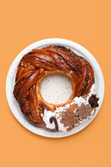 Plate with tasty Christmas pastry wreath on color background