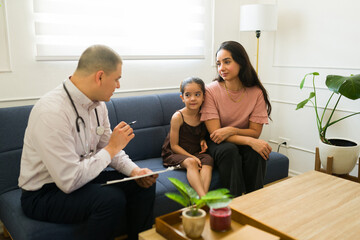 Pediatrician talking to the kid and mother during a doctor's visit