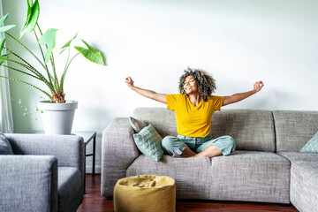 Happy afro american woman relaxing on the sofa at home - Smiling girl enjoying day off lying on the...
