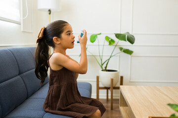Cute kid sick with asthma using the inhaler - obrazy, fototapety, plakaty