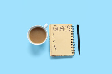 Notebook with empty to do list, pen and cup of coffee on blue background. New year goals