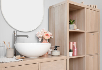 Sink bowl and bath accessories on wooden cabinet in bathroom