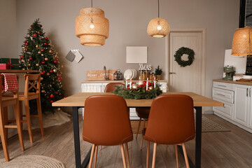 Interior of modern kitchen with glowing lamps, dining table and Christmas tree