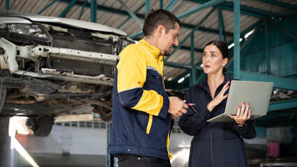 Two vehicle mechanic working together, conduct car inspection with laptop. Automotive service...