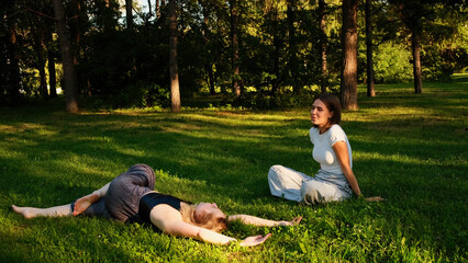 Rest on the grass. Concept. Two beautiful women spend time together talking and sunbathing in the sun in the forest.