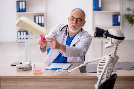 Old male doctor examining skeleton in the clinic