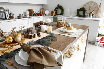 Christmas setting with burning candles on dining table in kitchen