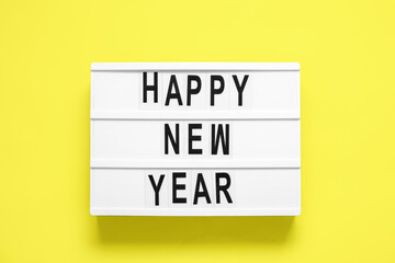 Board with text HAPPY NEW YEAR on yellow background