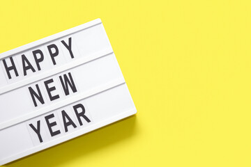 Board with text HAPPY NEW YEAR on yellow background