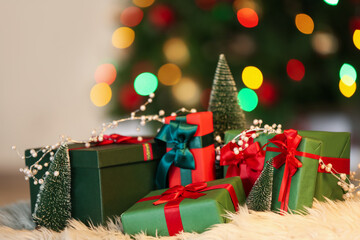 Different gift boxes on fur rug against blurred lights in living room, closeup