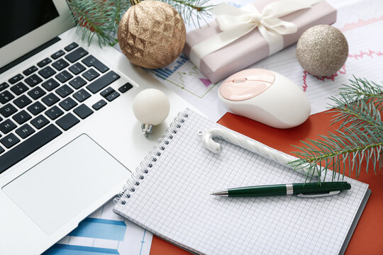 Laptop with office supplies and Christmas decor on brown background, closeup - Powered by Adobe