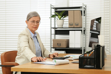 Senior accountant working at wooden desk in office