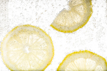 Juicy lemon slices in soda water against white background, closeup