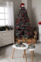 Interior of living room with Christmas tree, chest of drawers and coffee table