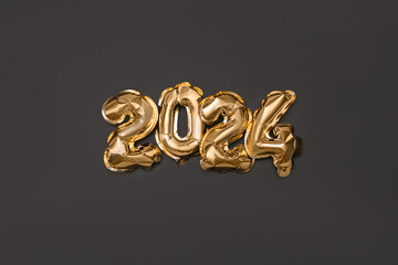 Golden foil balloons number 2024 on black background. New year concept.