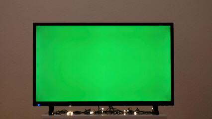 Green TV screen with flashing garland. Concept. Garland flashes on background of green TV in room. Green screen TV in empty room with festive atmosphere