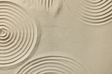 Fototapeta na wymiar Beautiful patterns drawn on sand, top view with space for text. Zen garden