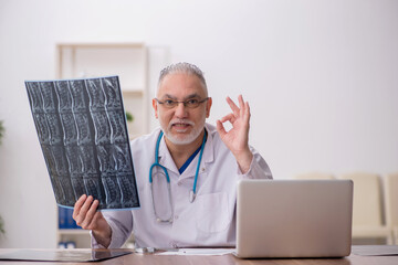 Old male doctor radiologist working in the clinic