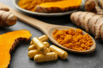 Aromatic turmeric powder, pills and raw roots on grey table, closeup