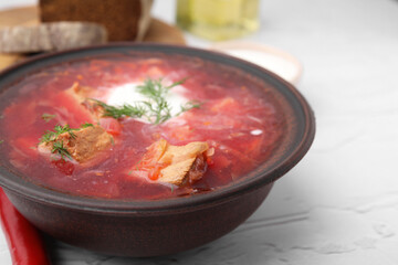 Tasty borscht with sour cream in bowl on white textured table, closeup