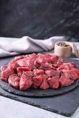 Pieces of raw beef meat and thyme sprigs on grey textured table. Space for text