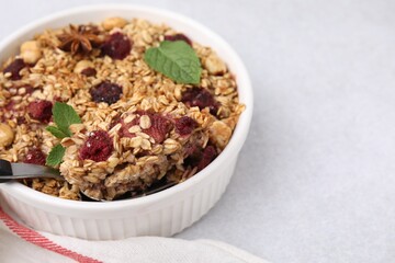 Tasty baked oatmeal with berries and nuts on light table, closeup. Space for text