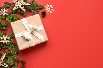 Christmas tree branches with gift box and decorations on red background