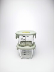 Special glass jar for storing baby food with measuring instructions isolated on white background....