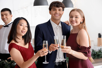Group of young people with champagne celebrating Christmas in kitchen