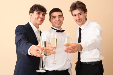 Young men with champagne celebrating Christmas on beige background