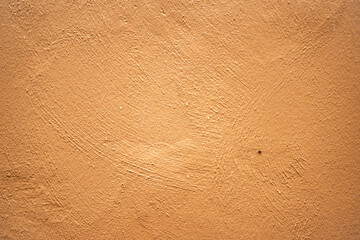 Mur de façade crépi et peint en brun orangé.