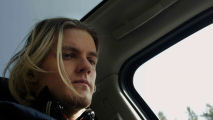 Low angle view of a man passenger inside car. Stock. Man with blond dyed hair looking worried and...