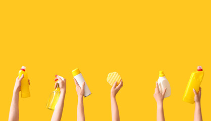 Women with cleaning supplies on yellow background