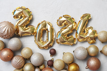 Composition with figure 2024 made of foil balloons and Christmas balls on grey background