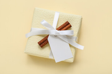Christmas gift box and cinnamon on yellow background