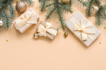 Christmas tree branches with balls and gift boxes on beige background