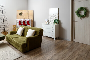 Interior of living room with sofa and Christmas wreath on door