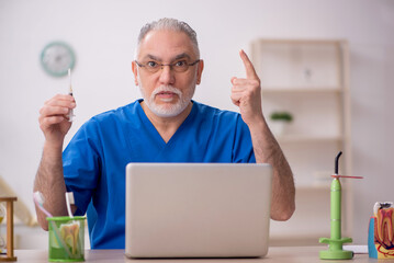 Old male dentist working in the clinic