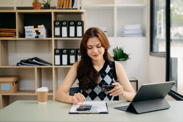 businesswoman hand using smart phone, tablet payments and holding credit card online shopping, omni channel, digital tablet docking keyboard computer at office in sun light..