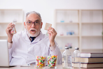 Old male doctor suggesting pills in the clinic