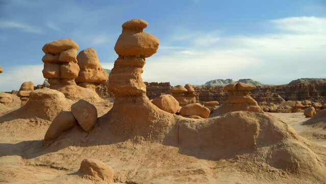 Slow panning view of the hoodoos in Goblin Valley as the sun glows from the formations.