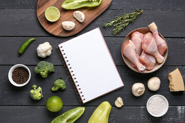 Blank notebook with fresh vegetables on black wooden table