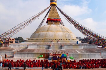 A serene congregation of Tibetan monks gathers in quiet contemplation, encircling the majestic...