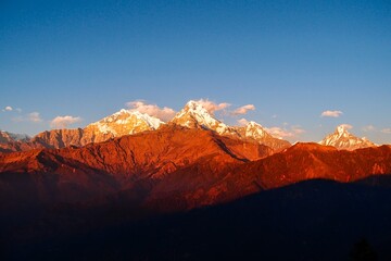 Vibrant hues of red and gold paint the majestic Annapurna ranges and iconic Mt. Machapuchare during...